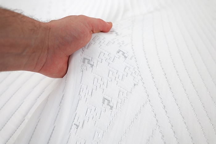 Hand feeling the top cover of the bedgear m3 performance mattress